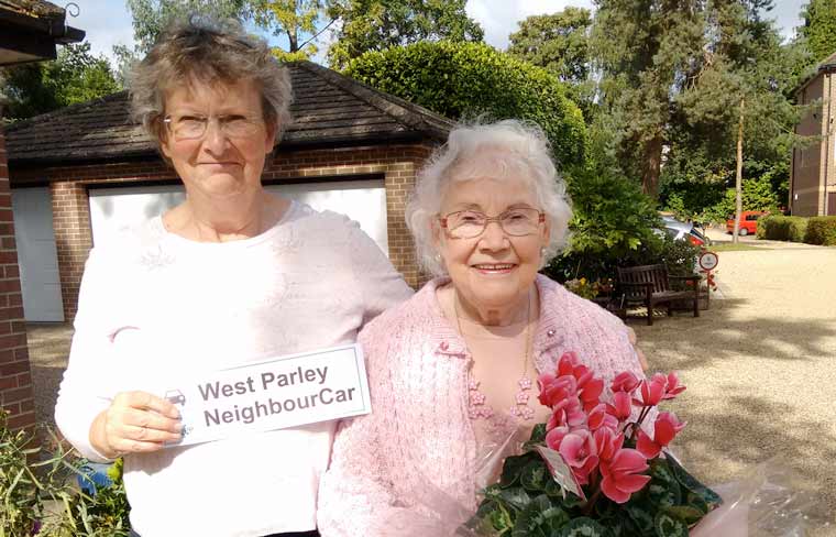 Peta Coussell presents Mrs Patricia Venn with a cyclamen plant to celebrate West Parley NeighbourCar's 2,000th trip