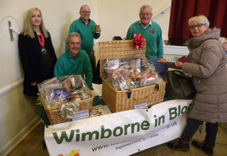 The Mayor of Wimborne Minster Cllr Mrs Kelly Webb visits the Wimborne in Bloom stall with Wimborne in Bloom members John Allen (seated), Terry Wheeler and Richard Nunn with Pauline Wheeler buying her raffle tickets