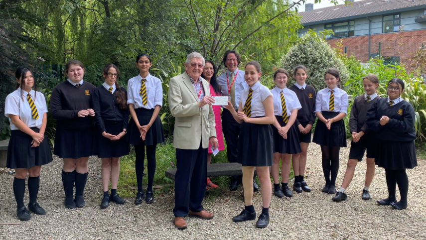 Isabella receives her bursary cheque from Wimborne Rotarian, Darryl Reach, watched by some of her friends at Allenbourn Middle School and her parents, Martin and Elizabeth Haynes (centre rear)