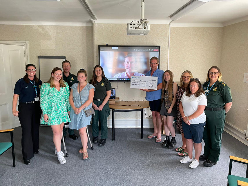 Rhys' family and friends alongside SWASFT colleagues at the presentation for the money raised by climbing Mount Snowdon. Rhys' father Nigel is presenting the cheque