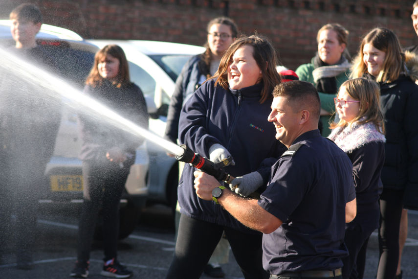 Fun with a fire hose - Springbourne Fire Station crew manager Adam Moss assists as the children get to grips with some of the skills required for fighting fires photograph by Hattie Miles