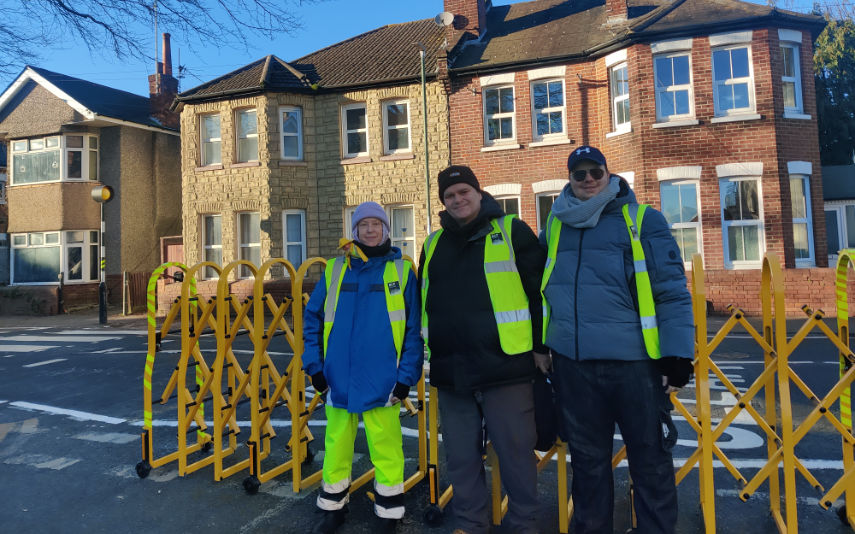 School Streets volunteers Tanya White, Mike Manser and Phil Newton in front of the road barrier for St Clement’s and St John’s Church of England Infant School